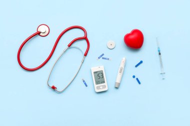 Mavi arka planda neşter, şerit ve steteskoplu glukometre. Diyabet kavramı