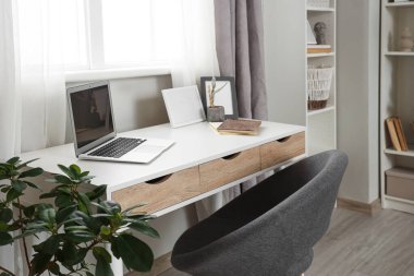 Yatak odasının içinde dizüstü bilgisayarı ve raf ünitesi olan bir iş yeri.