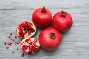 Gri ahşap arka planda tohumlarla taze olgun narlar.