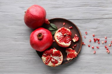 Taze olgun narlar ve gri ahşap arka planda tohumlarla dolu bir tabak.