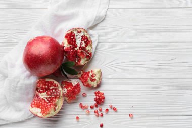 Tohumlarla taze nar ve beyaz ahşap arka planda yapraklar.