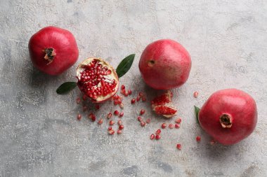 Gri arka planda tohum ve yapraklarla taze olgun narlar.