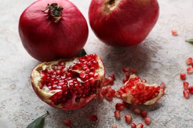 Gri arka planda tohumları olan taze olgun narlar, yakın plan.