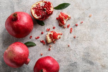 Gri arka planda tohum ve yapraklarla taze olgun narlar.