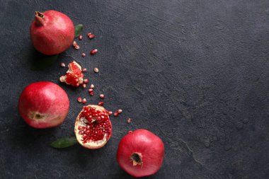 Koyu arkaplanda tohum ve yapraklarla taze olgun nar.