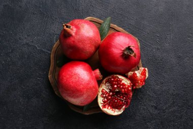 Koyu arkaplanda taze olgun nar bulunan ahşap tahta.