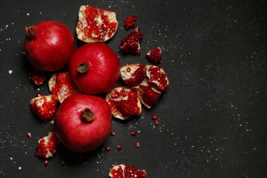 Siyah zemin üzerinde tohumları olan taze olgun narlar.