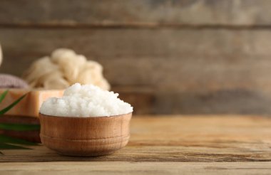 Tahta arka planda bir kase doğal vücut fırçası, sabun ve banyo süngeri.