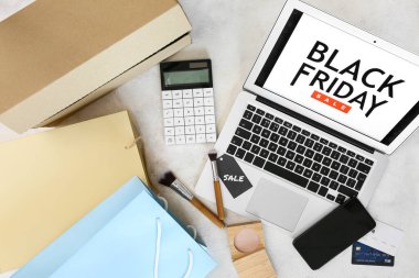 Siyah Cuma satışı yazılı dizüstü bilgisayar, makyaj fırçaları, cep telefonu ve açık arkaplanda alışveriş çantaları