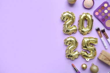 Makyaj ürünleri ve eflatun arkaplanlı Noel toplarıyla 2025