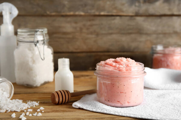 Jars of natural body scrubs and cosmetics on wooden table