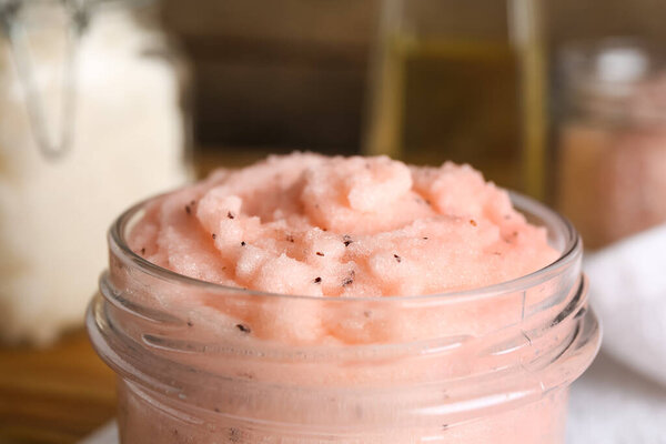 Glass jar of natural body scrub on blurred background, closeup