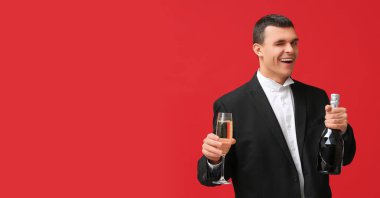 Kırmızı arka planda şampanya içen mutlu genç adam mesaj için yer açtı.