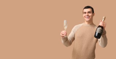 Bej arka planda şişe ve bir bardak şampanyası olan genç bir adam. Mesaj için yeri var.