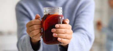 Evde elinde mason kavanozu olan sıcak şarap taşıyan bir kadın, yakın plan.