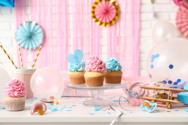 Bebek emziği ve beyaz tuğlalı arka planda süslemeleri olan lezzetli kekler. Cinsiyet ortaya çıkan parti kavramı