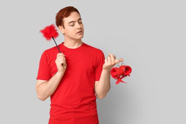 Gri arka planda farklı seks oyuncakları olan yakışıklı bir genç.