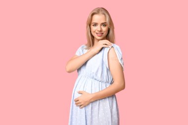 Pembe arka planda uygulamalı tıbbi yaması olan güzel hamile bir kadın.