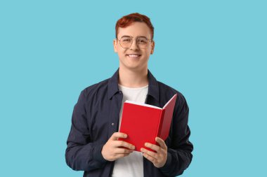 Gözlüklü genç adam arka plan hakkında kitap okuyor.