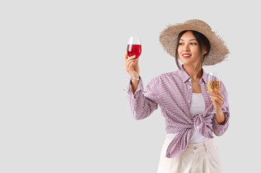 Hafif arka planda şarap kadehleri olan genç Asyalı kadın.