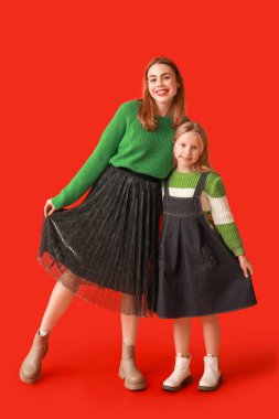 Sevimli küçük kız ve annesi kırmızı arka planda.