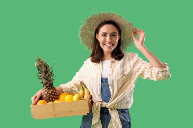 Yeşil arka planda bir kutu meyvesi olan kadın çiftçi.