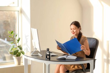 Ofiste çalışan dosyasıyla genç Asyalı iş kadını.