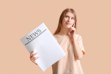 Renk duvarının yanında boş gazetesi olan düşünceli genç bir kadın.