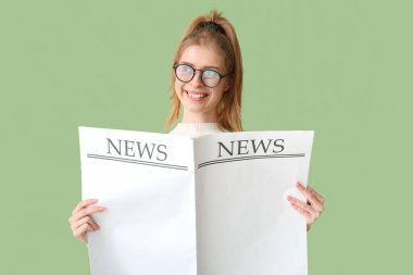 Yeşil duvarın yanında boş gazetesi olan güzel genç bir kadın.