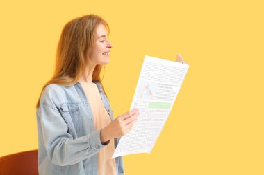 Renkli arka planda gazete okuyan duygusal genç bir kadın.