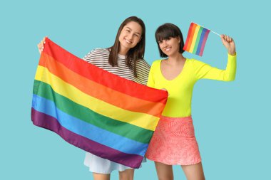 Mavi arka planda LGBT bayrakları olan genç lezbiyen çift