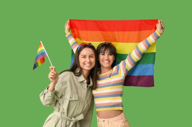 Yeşil arka planda LGBT bayrakları olan genç lezbiyen çift