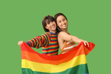 Yeşil arka planda LGBT bayrağı olan genç lezbiyen çift