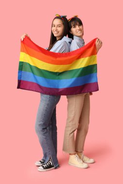 Pembe arka planda LGBT bayrağı olan genç lezbiyen çift
