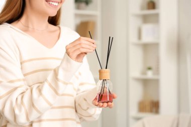 Evde sazlık difüzörü olan genç bir kadın.