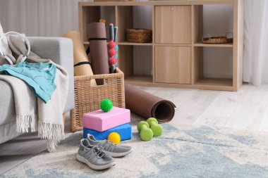 Spor ayakkabılar, hasır sepet ve oturma odasındaki farklı spor aletleri.