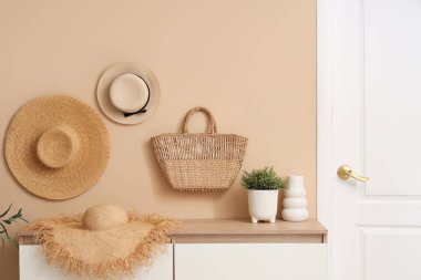 Hasır şapkalı sandıklar, hasır çanta ve koridorda saksılar.