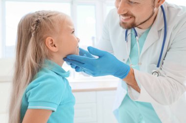 Erkek endokrinolog, klinikte küçük bir kızın tiroit bezini inceliyor.