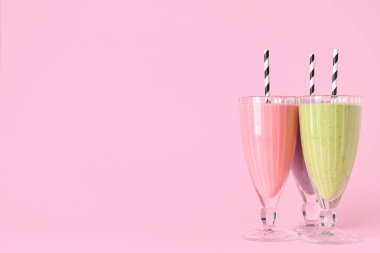 Pembe arka planda farklı taze meyve suyu bardakları.