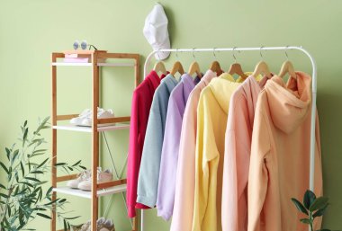 Odada yeşil duvarın yanında giysilerle dizilin.