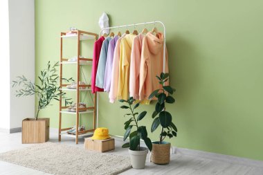 Odadaki yeşil duvarın yanında asılı giysilerle dizilin.