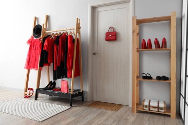 Siyah ve kırmızı elbiseli raflar ve beyaz duvarın yanındaki ayakkabılar için.