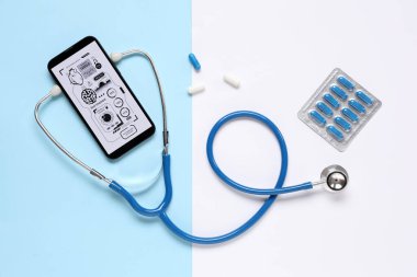 Steteskoplu cep telefonu ve renkli arka planda haplar. Teletıp kavramı