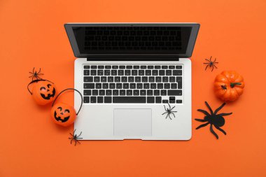 Turuncu arka planda Cadılar Bayramı için modern dizüstü bilgisayar ve dekor kompozisyonu
