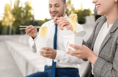 İş arkadaşları öğle arasında Asya eriştesi yiyor. Kapalı mekanda.