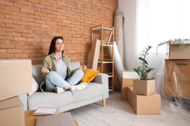 Güzel bir kadın taşınma gününde odada meditasyon yapıyor.
