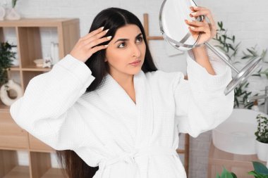 Evde aynaya bakarken saç dökülme sorunu olan hamile bir kadın.