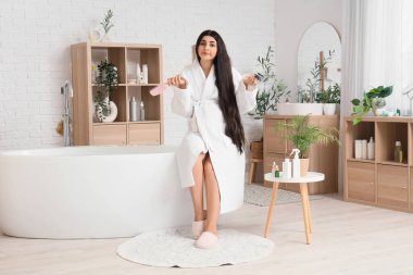 Saç dökülmesi sorunu olan ve banyoda fırça çeken hamile bir kadın.