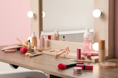Dekoratif makyaj malzemeleri ve makyaj aksesuarlarıyla birlikte pembe duvarın yanında.