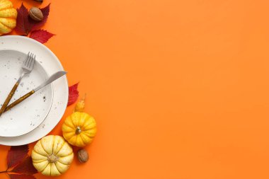 Turuncu arka planda taze kabak, ceviz ve sonbahar yapraklarıyla güzel bir masa.